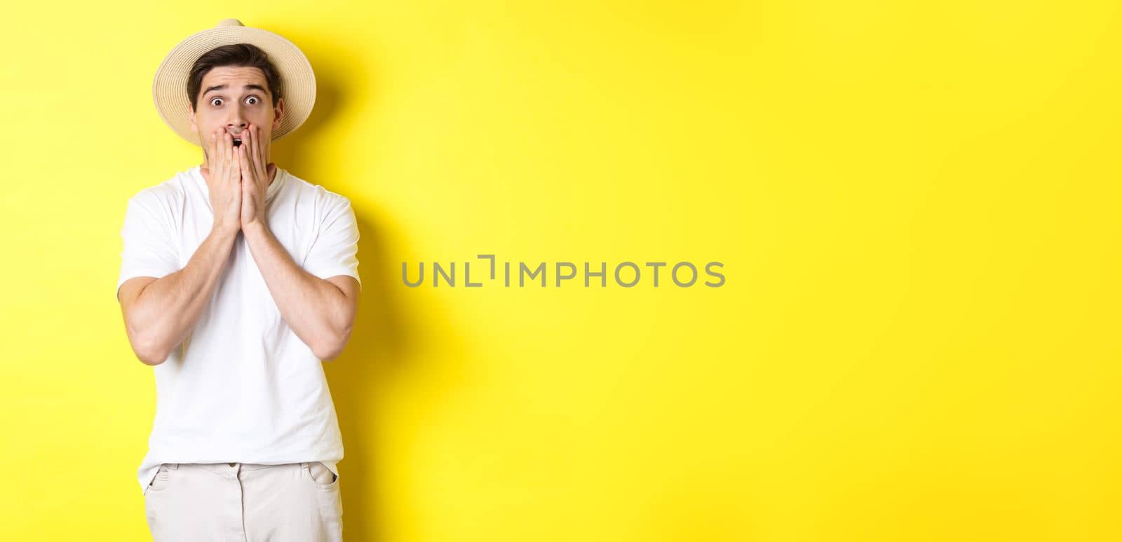 Concept of tourism and summer. Shocked guy jumping from fear, standing startled against yellow background.