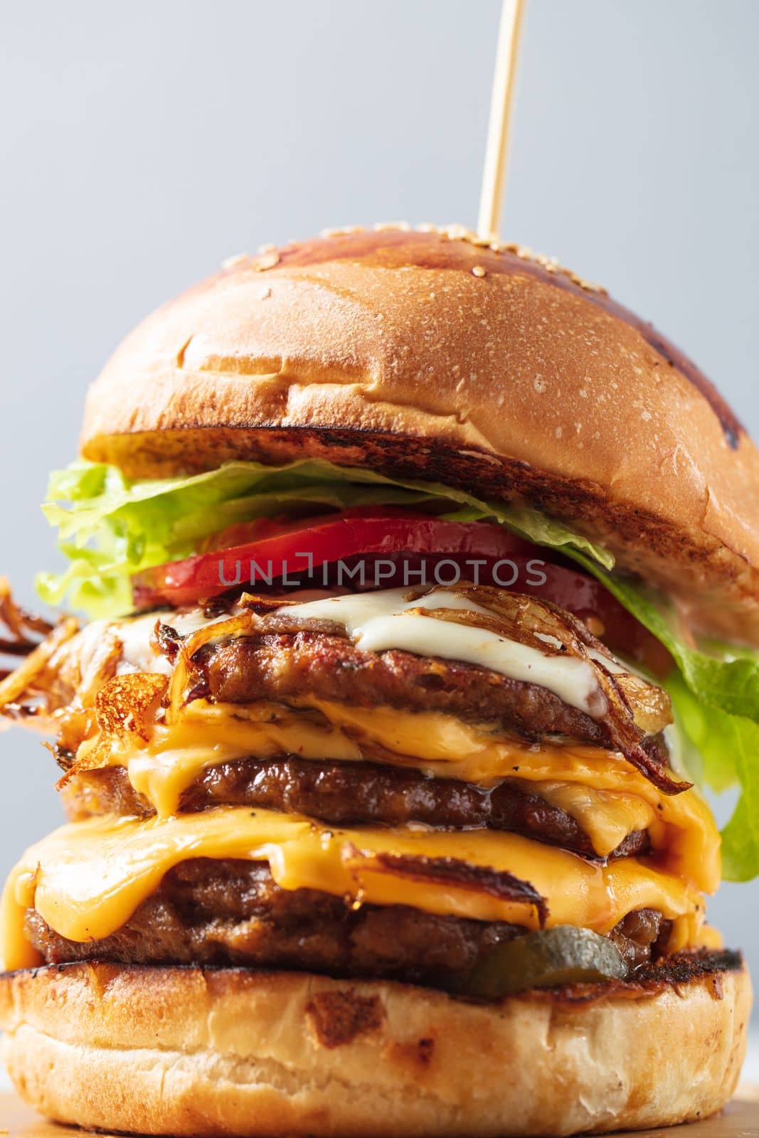 Loaded cheeseburgers three triple, stacked patties stacked high with layers of cheese, lettuce, and tomato. Tall cheeseburger. High quality photo