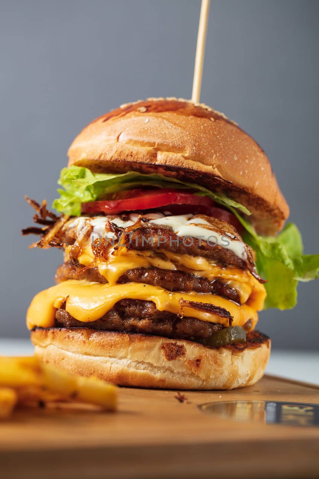 Loaded cheeseburgers three triple, stacked patties stacked high with layers of cheese, lettuce, and tomato. Tall cheeseburger. High quality photo