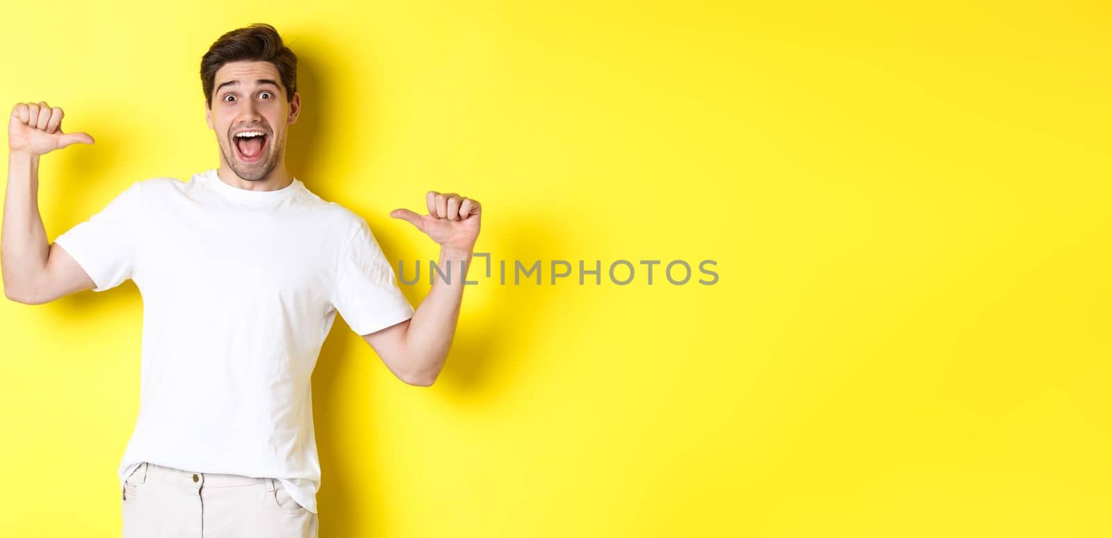 Excited man looking happy, pointing at himself with amazement, standing over yellow background by Benzoix