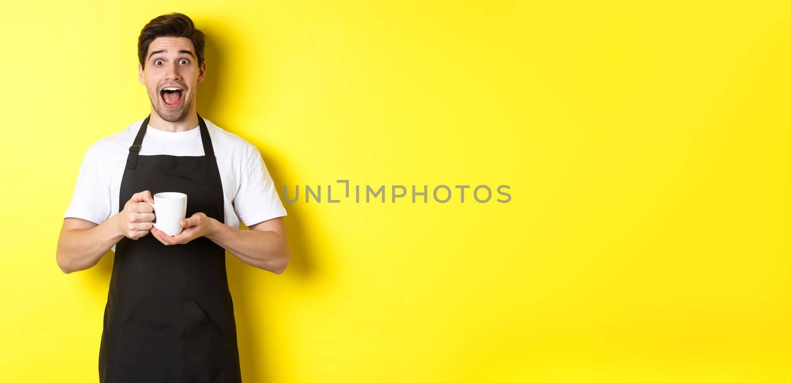 Friendly coffee shop waiter standing with raised hands, place for your sign or logo, standing over yellow background.