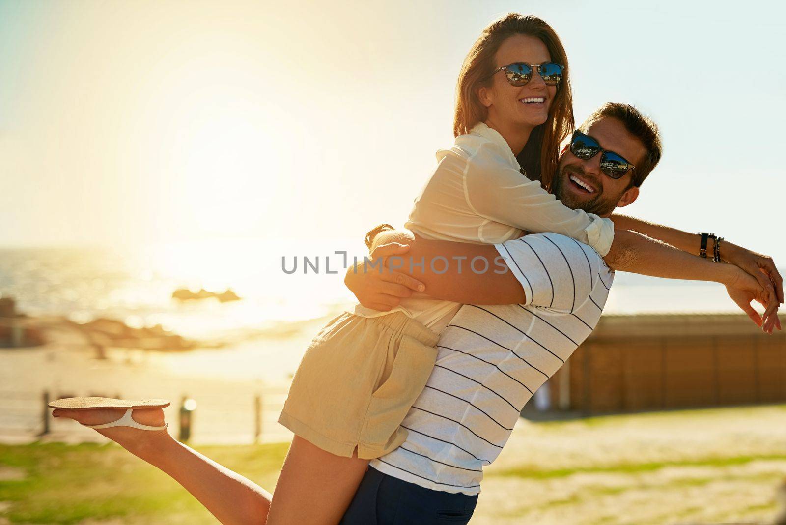 Romance comes alive in summer. a happy young couple embracing on a summers day outdoors. by YuriArcurs