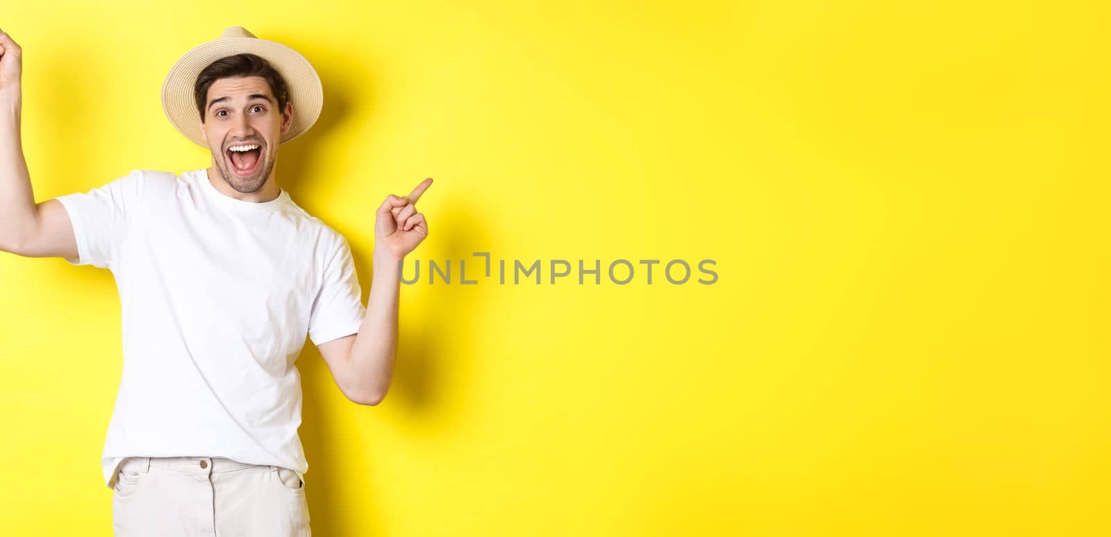 Concept of tourism and lifestyle. Happy tourist dancing and pointing fingers sideways, showing vacation variants, yellow background.