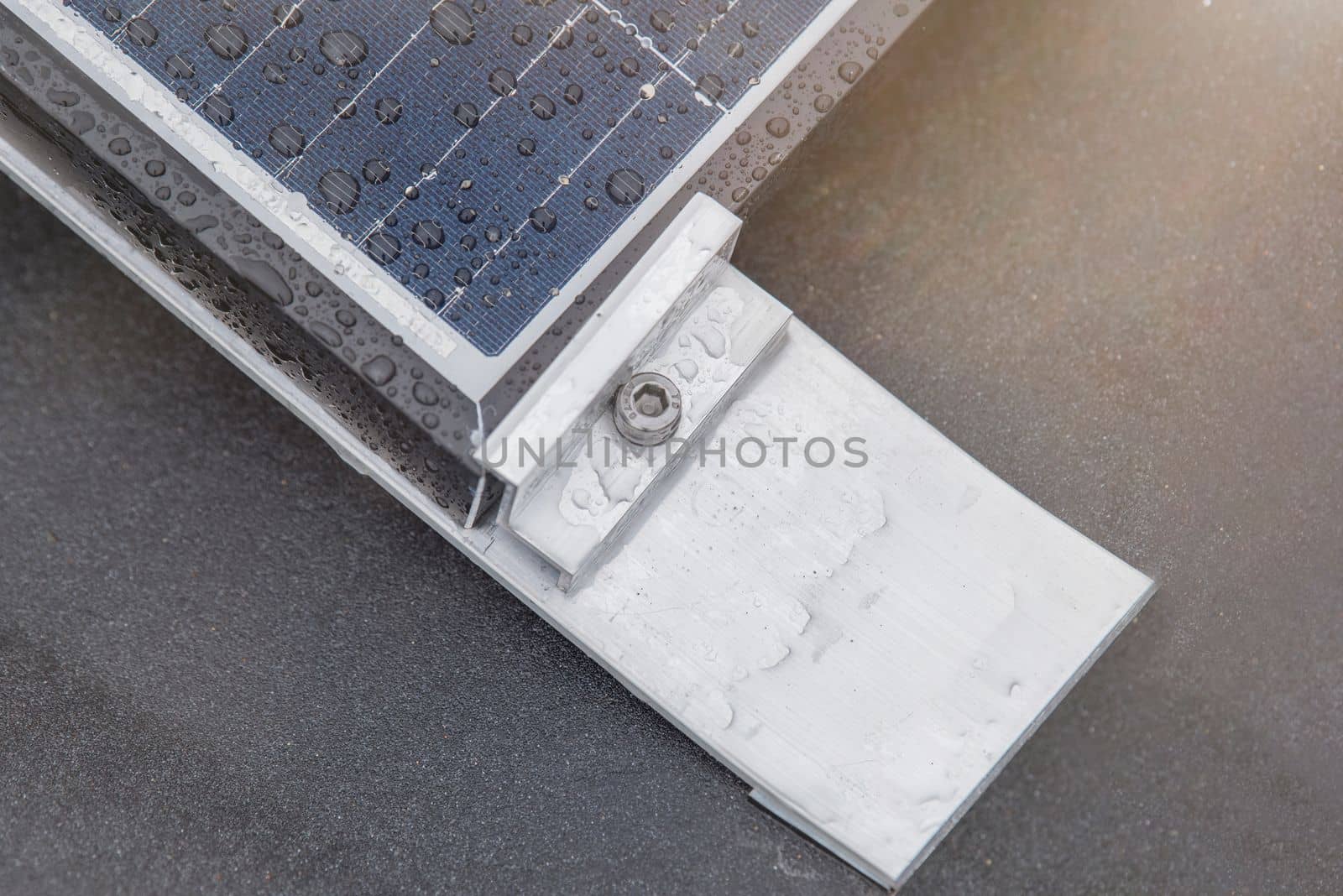 Bracket for mounting solar panels. Mounting a solar panel close-up on the roof of a residential building, water drops after rain, green energy production