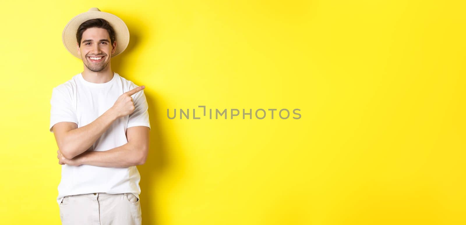 Young male tourist pointing finger right, smiling and showing advertisement, concept of tourism and lifestyle, yellow background.