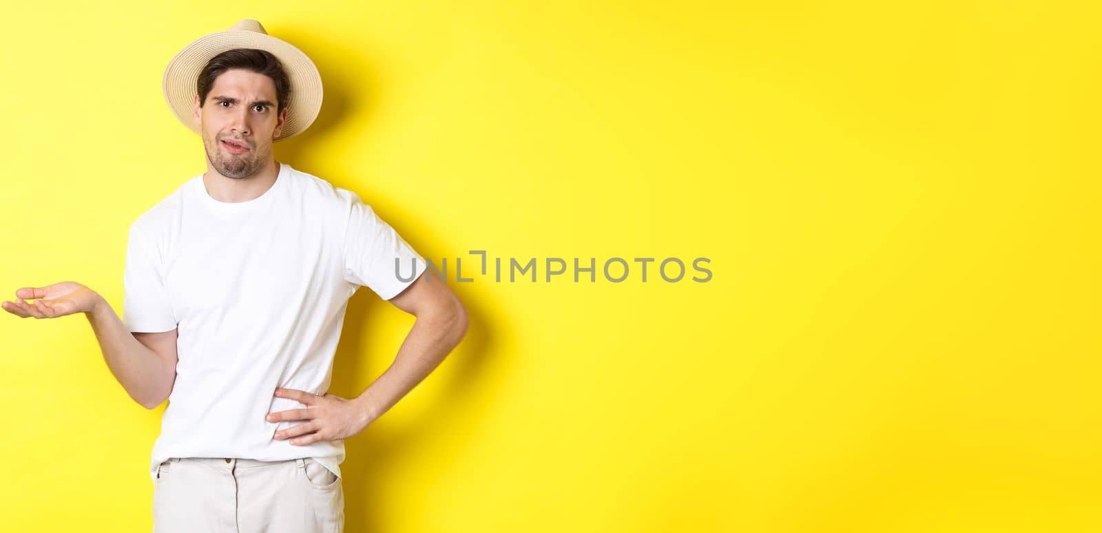 Concept of tourism and summer. Young skeptical tourist complaining, looking judgemental, standing over yellow background.