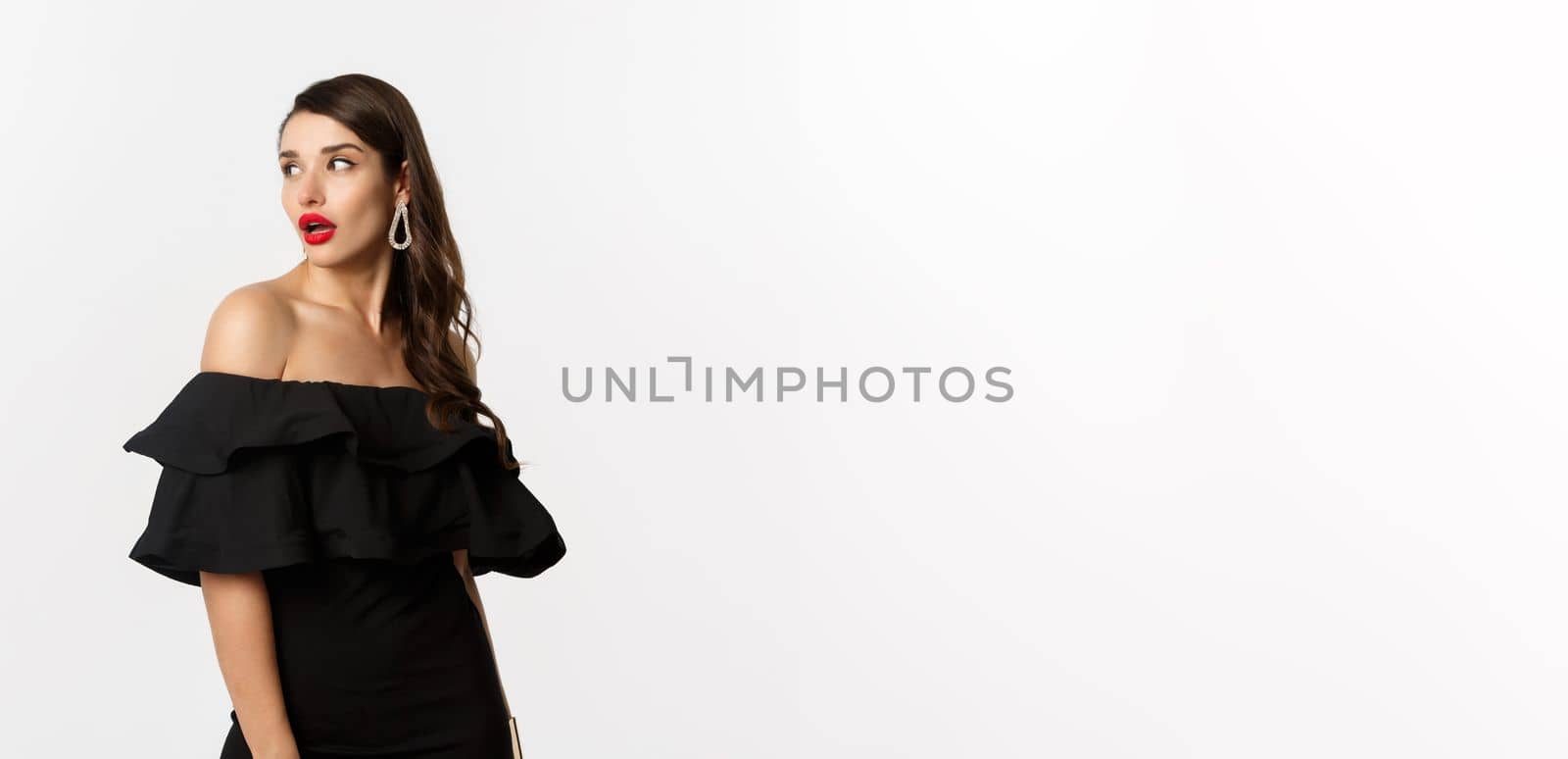 Fashion and beauty concept. Image of attractive young woman in black dress turn behind and looking at copy space, standing over white background by Benzoix