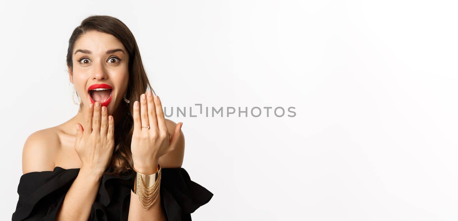 Excited woman showing engagement ring after saying yes to marriage proposal, bride looking excited, standing over white background.