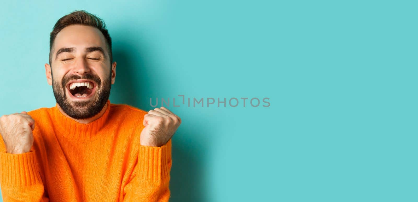 Image of handsome relieved man feeling satisfaction, rejoicing of winning or achievement, making fist pump and saying yes, standing over turquoise background by Benzoix