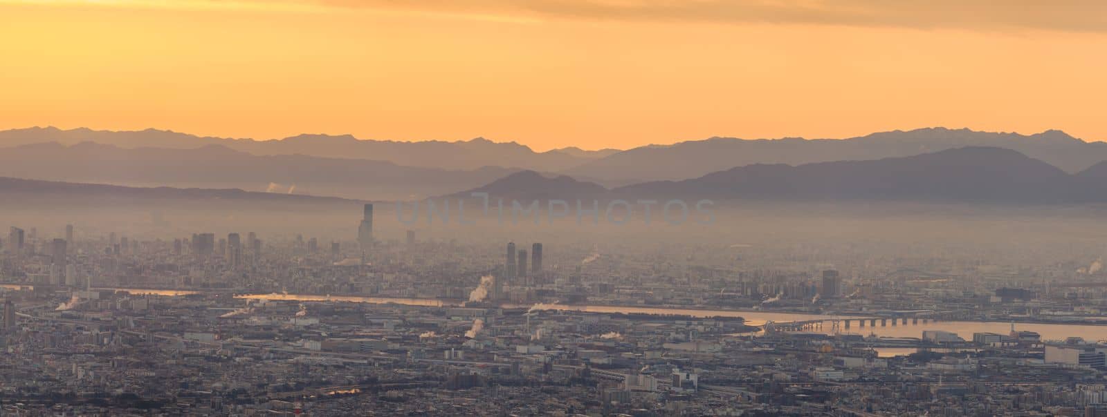 Panoramic view of haze layer over city with orange glow in sky at sunrise. High quality photo