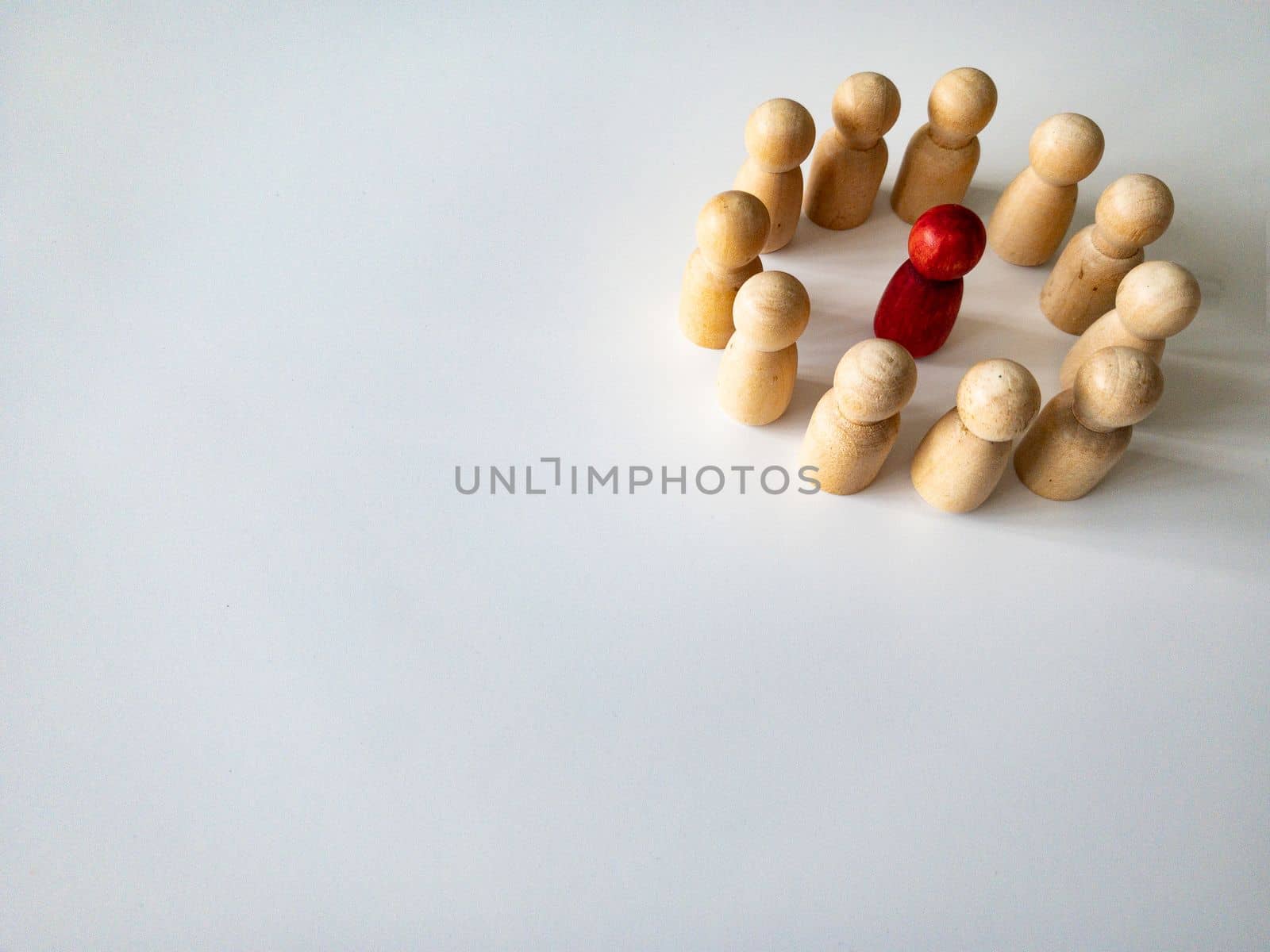 Red wooden doll figure surrounded by other doll figure on white background. Harassment and bully concept.