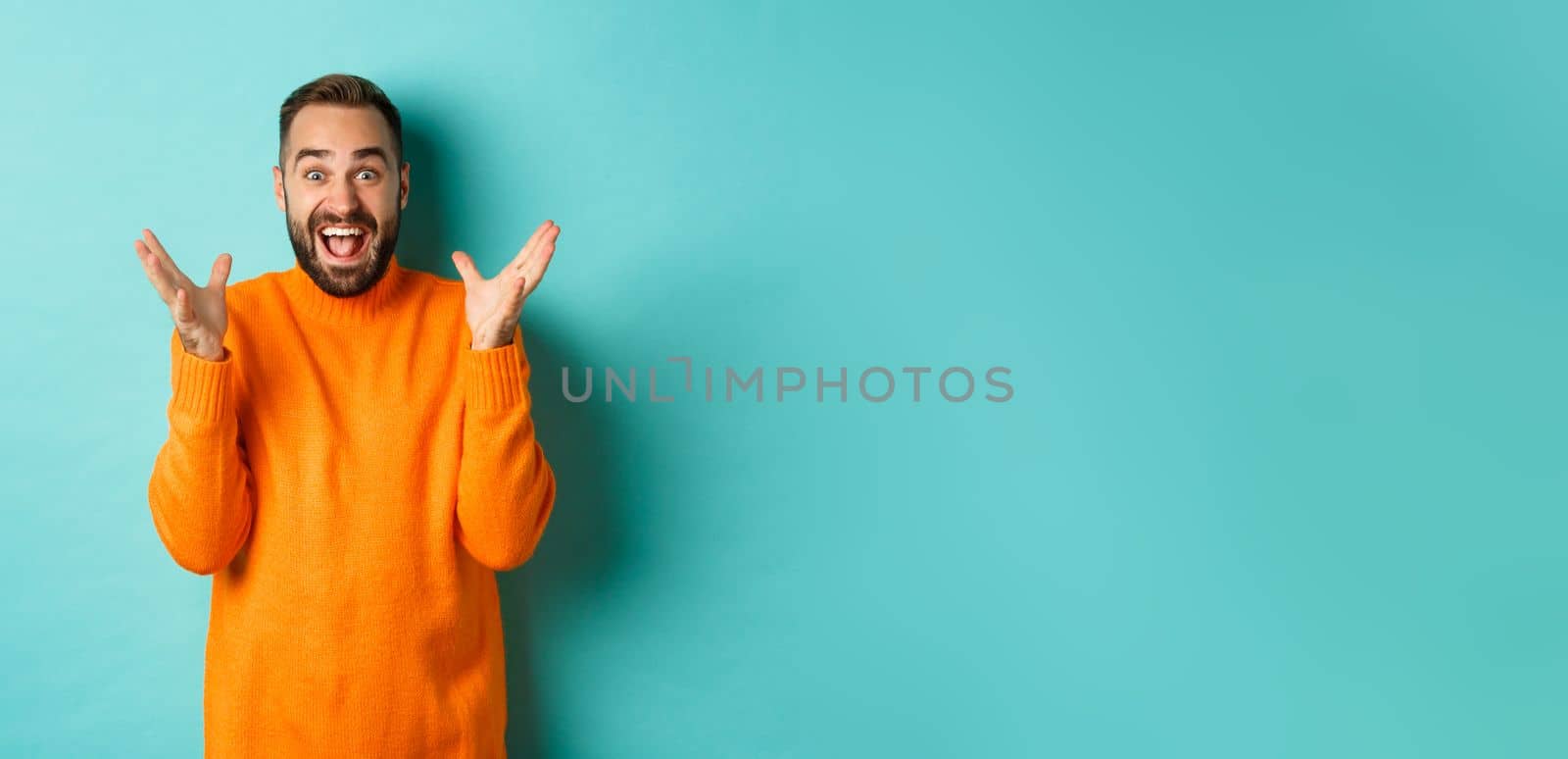 Image of excited and happy bearded man, shaking hands and smiling amazed, telling big news, standing over light blue background by Benzoix