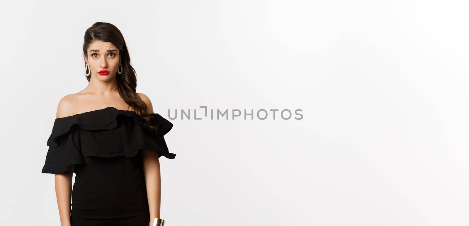 Fashion and beauty. Cute and timid young woman in black dress looking confused and sad at camera, cant understand, standing gloomy against white background by Benzoix