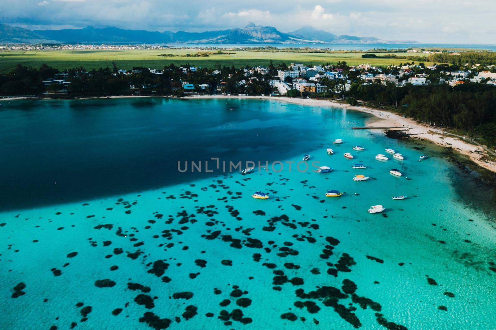 Aerial picture of the east coast of Mauritius Island. Beautiful lagoon of Mauritius Island shot from above. Boat sailing in turquoise lagoon.