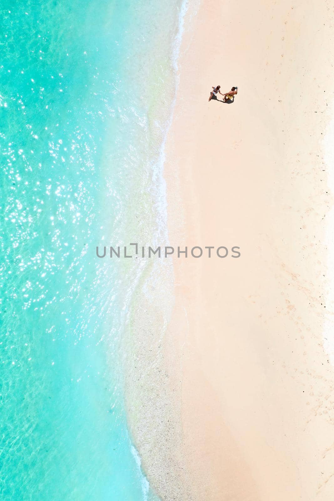 A couple walks along the Beach of Mauritius in the Indian ocean. Top view of the beach with turquoise water on the tropical island of Mauritius.Aerial photography