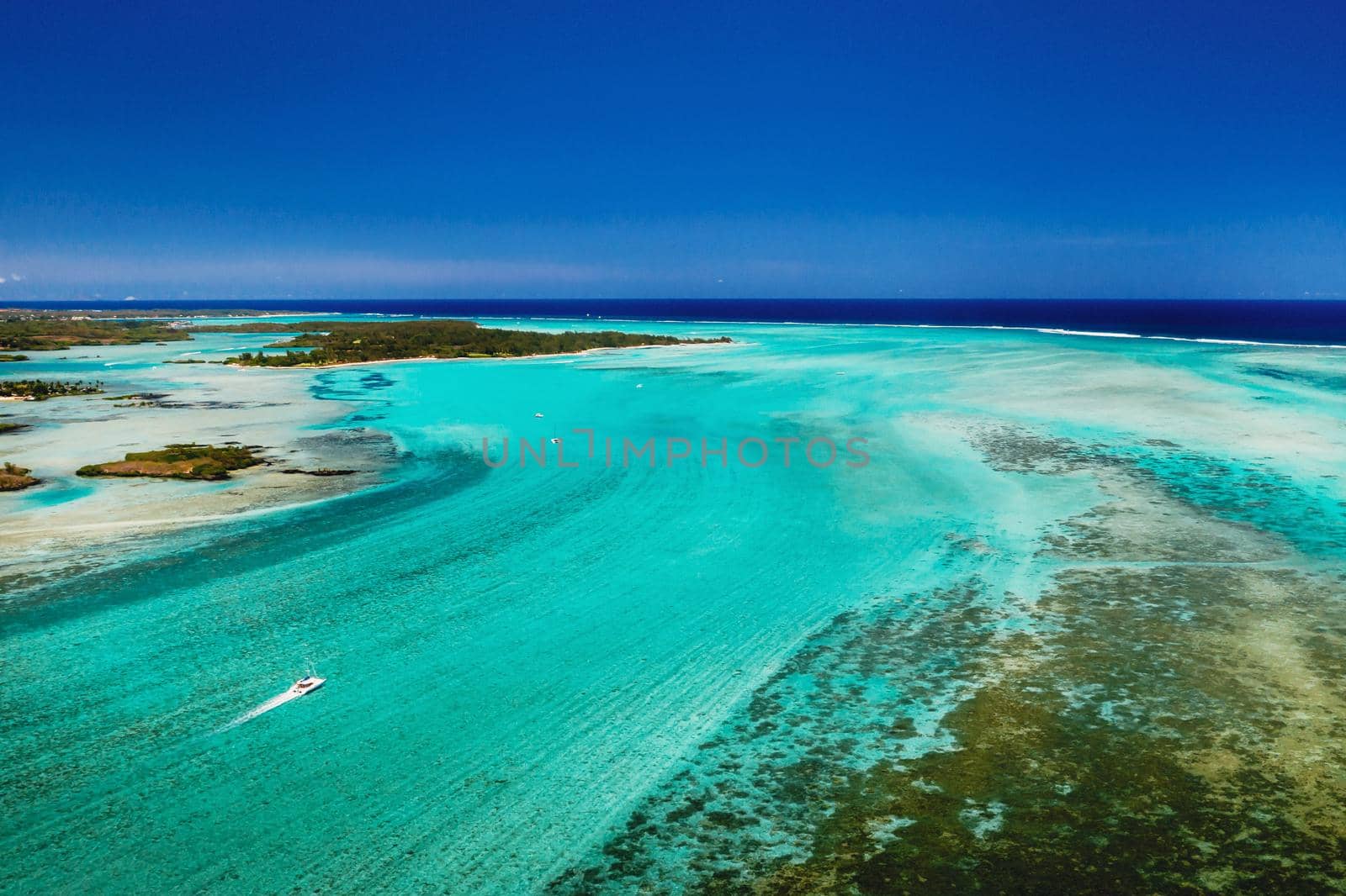 Aerial picture of the east coast of Mauritius Island. Beautiful lagoon of Mauritius Island shot from above. Boat sailing in turquoise lagoon by Lobachad