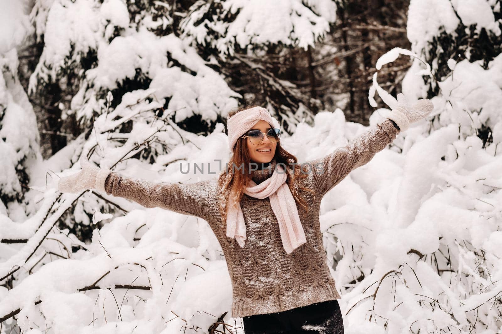 A girl in a sweater and glasses in winter in a snow-covered forest by Lobachad