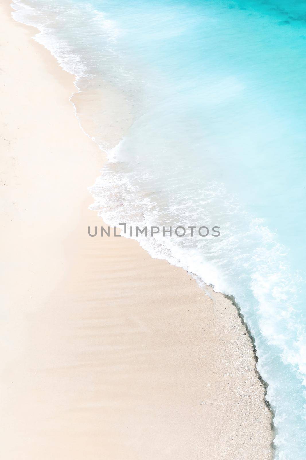 Tropical beach with a bird's eye view of the waves breaking on the tropical Golden sandy beach. Sea waves gently loop along the beautiful sandy beach. by Lobachad