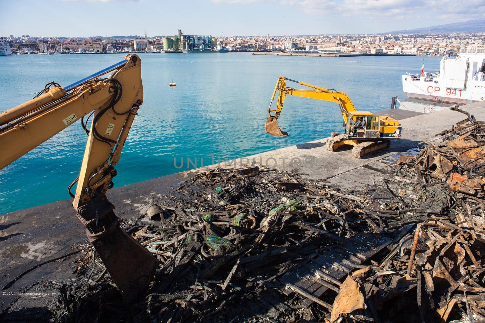 Cranes next to the piles of garbage and metal scrap in the Catania pier