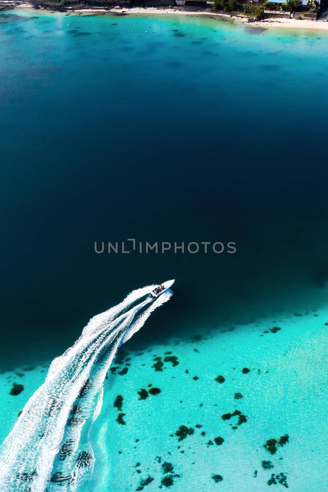 Top view of the Blue Bay lagoon of Mauritius. A boat floats on a turquoise lagoon by Lobachad