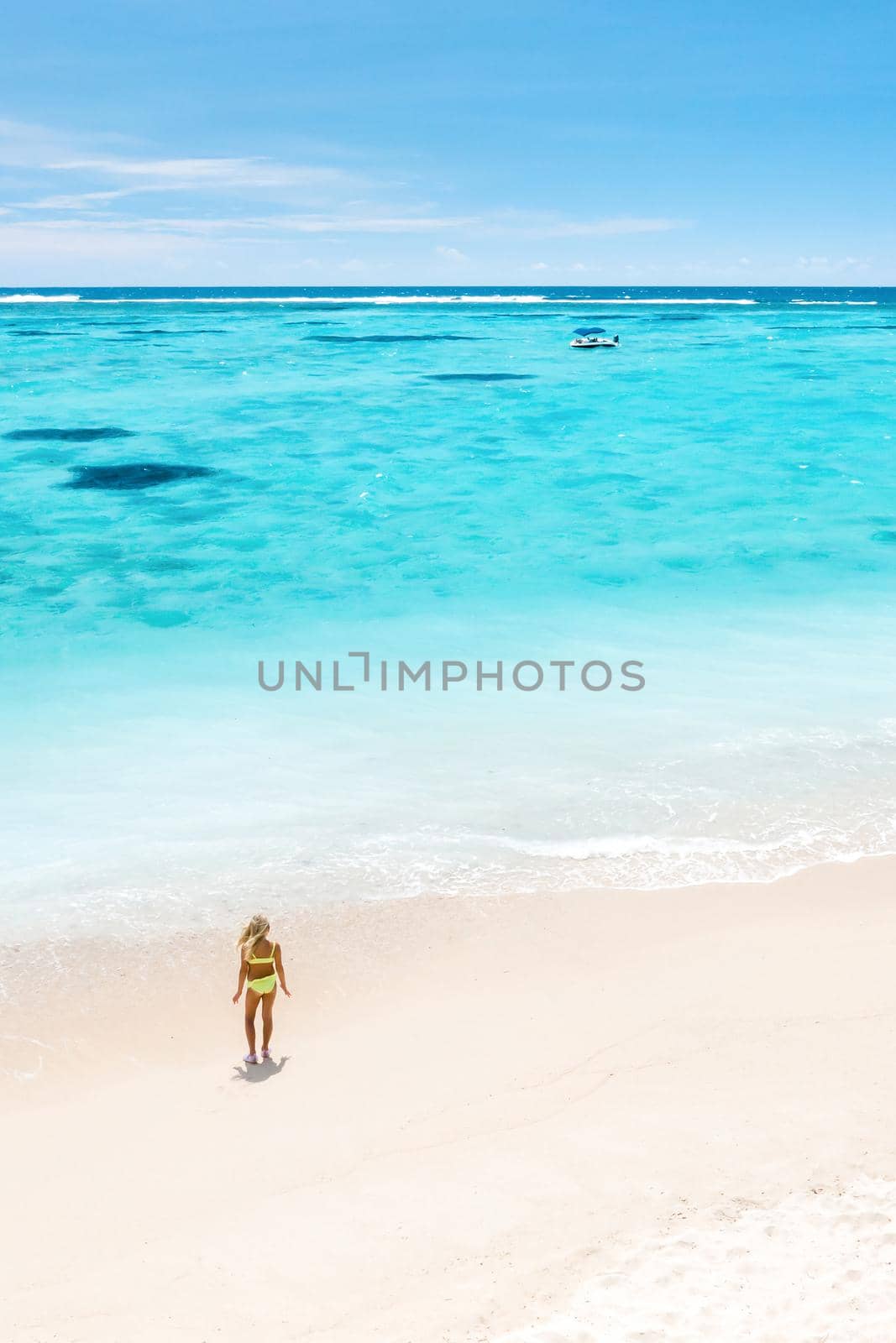 A little girl stands on Le Morne beach in the Indian Ocean on the island of Mauritius by Lobachad
