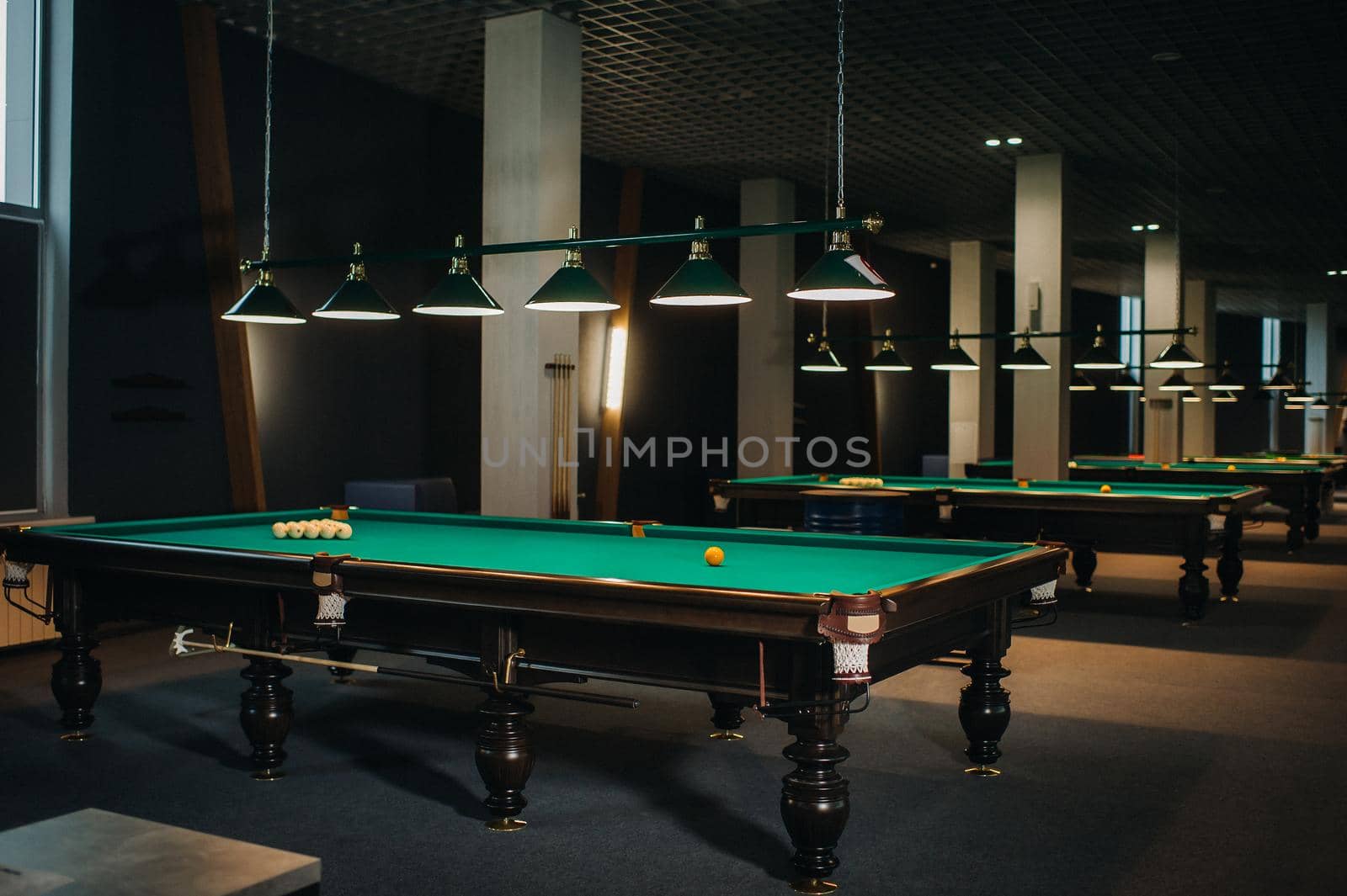 there are a lot of billiard tables with green surfaces and balls in the billiard club.