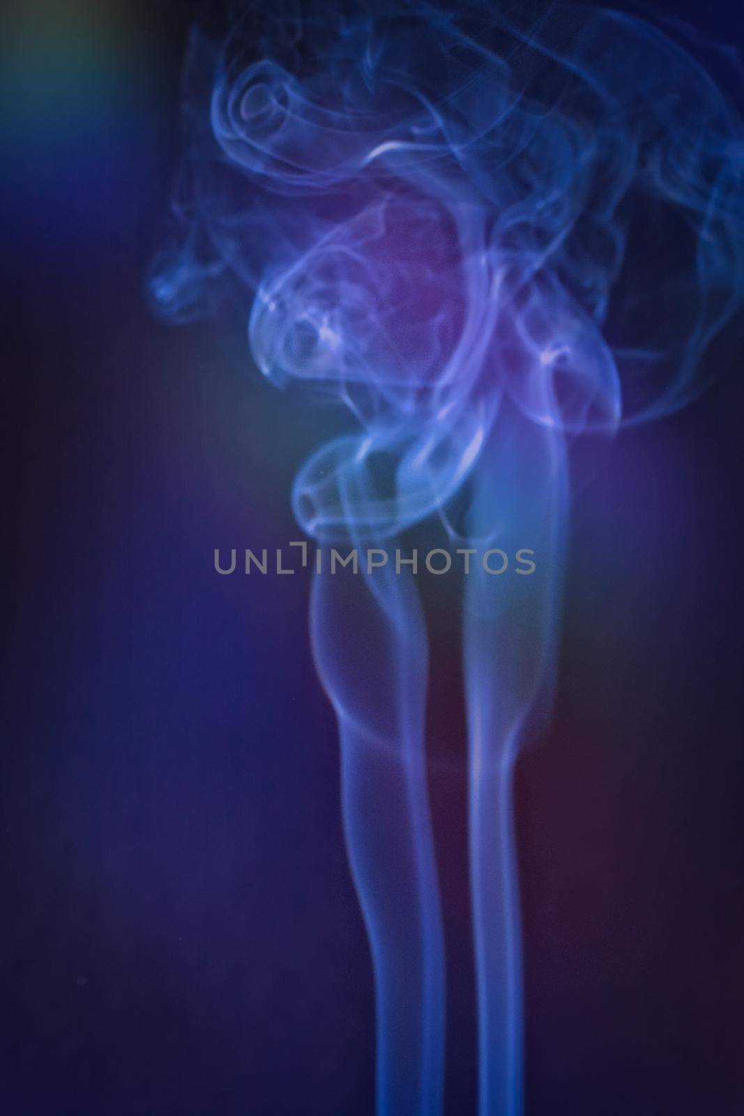 A vertical shot of smoke in colorfull backlight with a blue note