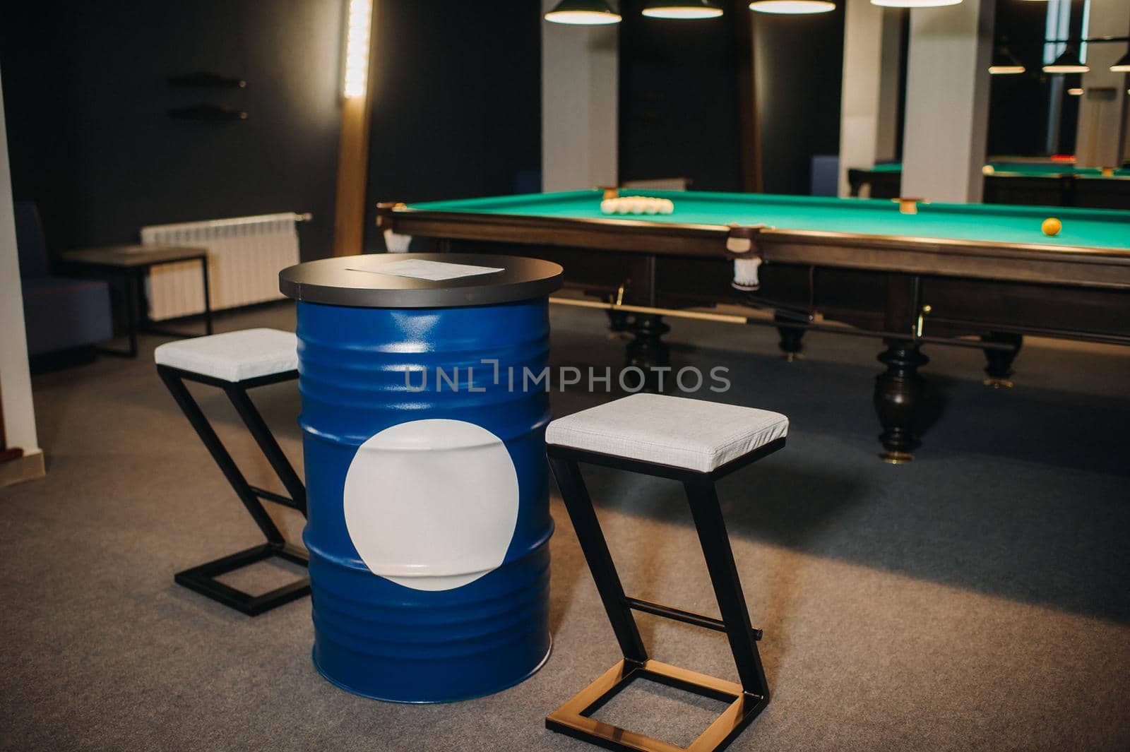 table and two chairs near the green-covered billiard table with balls in the billiard club.