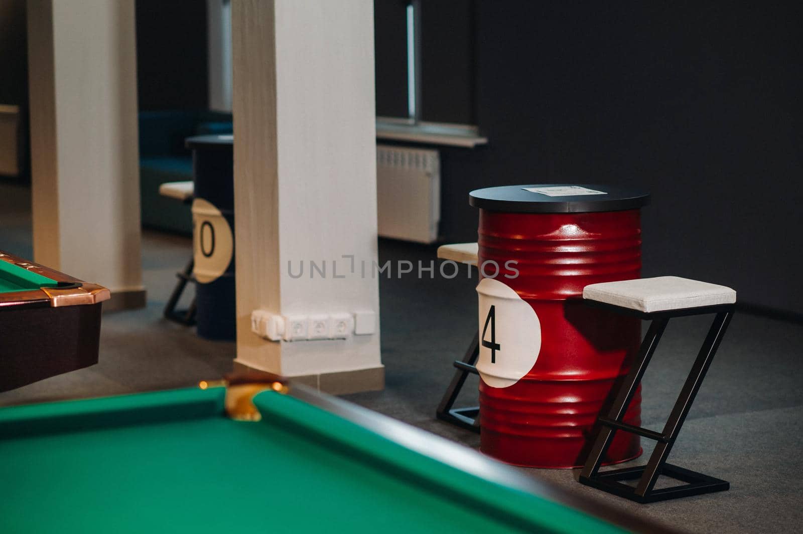 table and two chairs near the green-covered billiard table with balls in the billiard club.