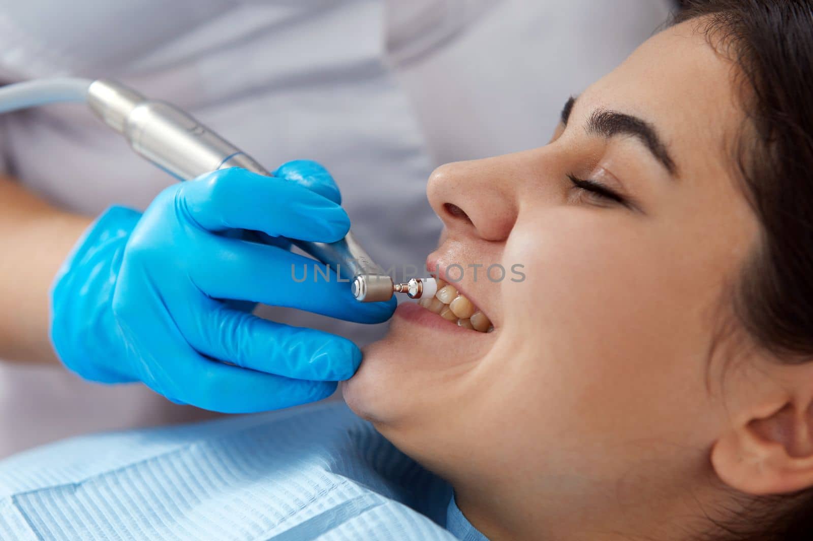 Young woman getting her teeth polished in dental clinic. Professional dental cleaning concept by Mariakray