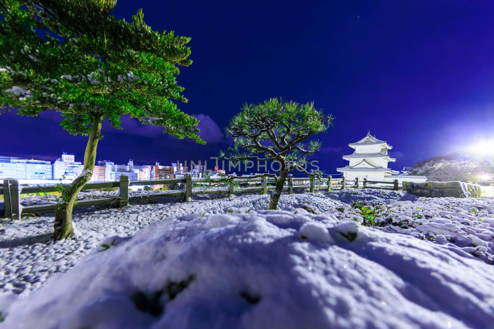 Snow covered landscape with Japanese castle and modern city at night. High quality photo