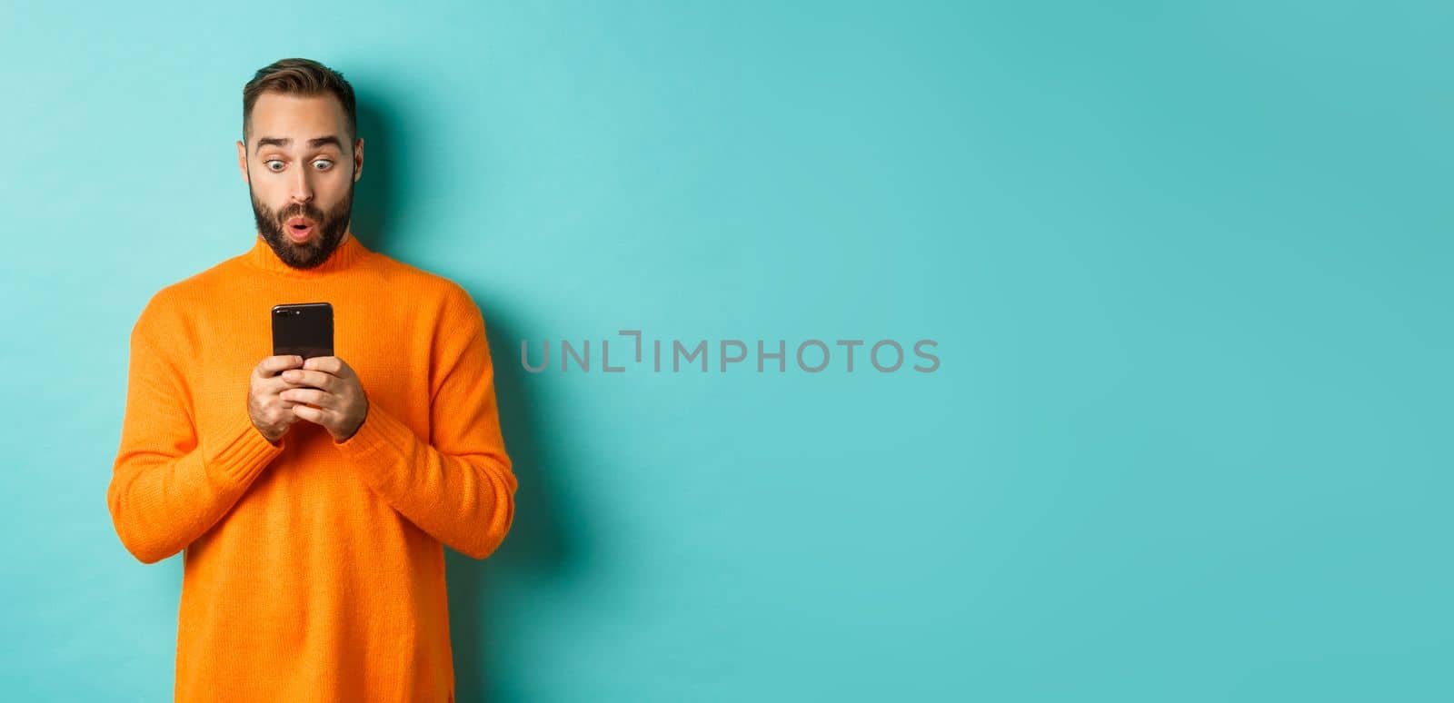 Image of man reading message with surprised face, standing amazed over light blue background by Benzoix