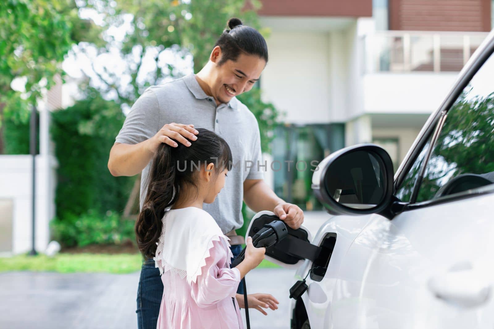 Progressive concept of father and daughter with EV car and home charging station by biancoblue