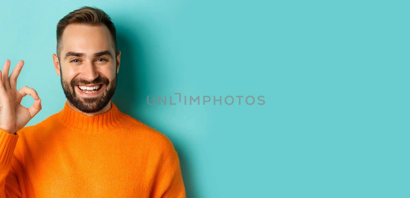 Close-up of assertive young man assuring everything ok, showing okay sign and smiling, yes or positive answer, standing over light blue background by Benzoix