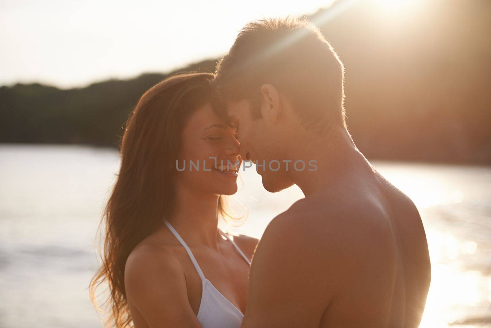 Nothing more romantic than a summer sunset. A young couple sharing a romantic moment while on a beach. by YuriArcurs