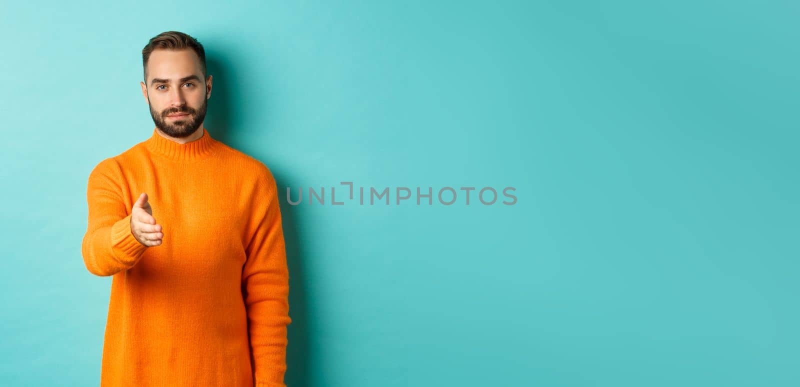 Confident man extending hand for handshake, greeting you, looking self-assured, standing over light blue background by Benzoix