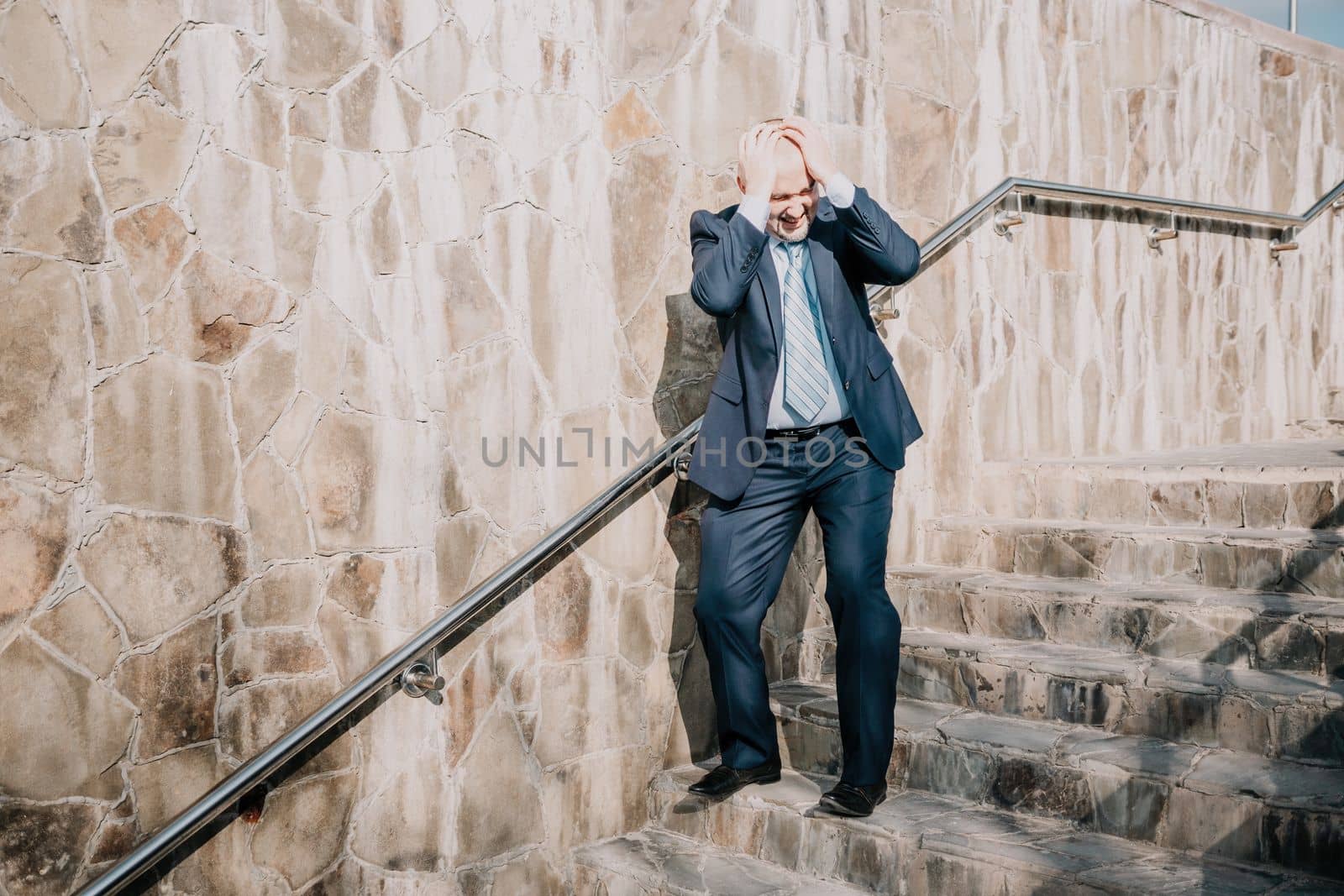 Portrait of a senior professional man in a suit with various problems. A middle-aged businessman with a briefcase descends the stairs.