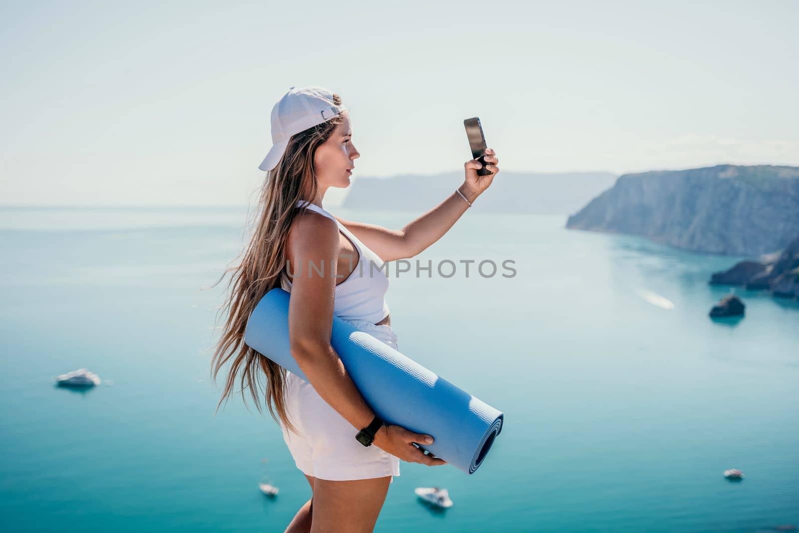 Young woman with black hair, fitness instructor in pink sports leggings and tops, doing pilates on yoga mat with magic pilates ring by the sea on the beach. Female fitness daily yoga concept