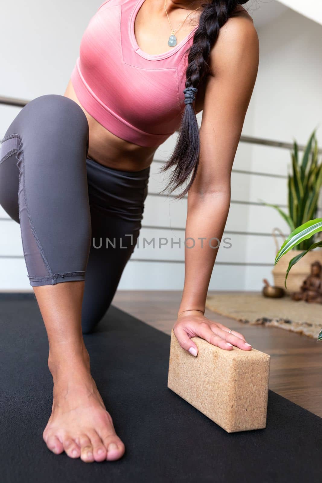 Unrecognizable woman doing yoga twist at home with help of cork yoga block. Vertical image. by Hoverstock