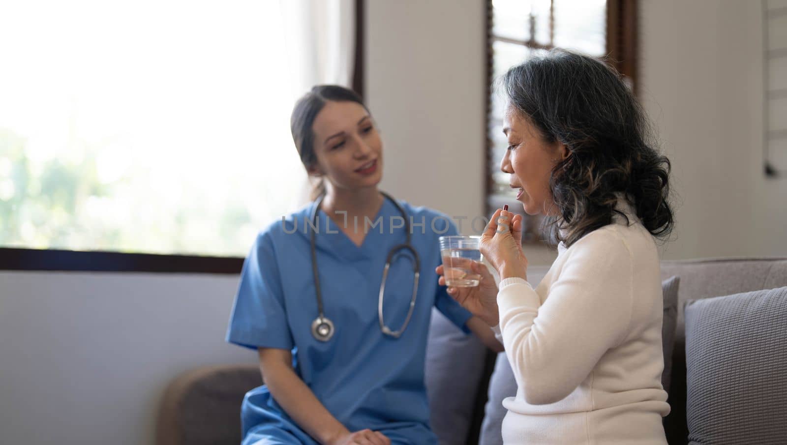 Asian nurse showing health checkup report to grandmather and giving advice. medical assisted living visit senior patient at home. Home nursing and healthcare caregiver concept..