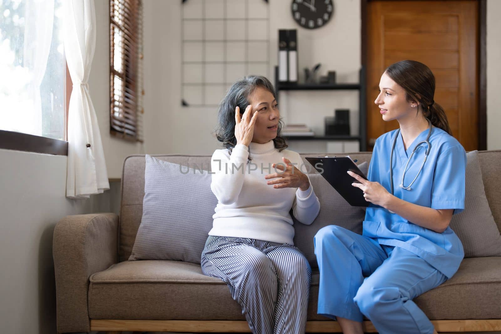 Asian nurse showing health checkup report to grandmather and giving advice. medical assisted living visit senior patient at home. Home nursing and healthcare caregiver concept..