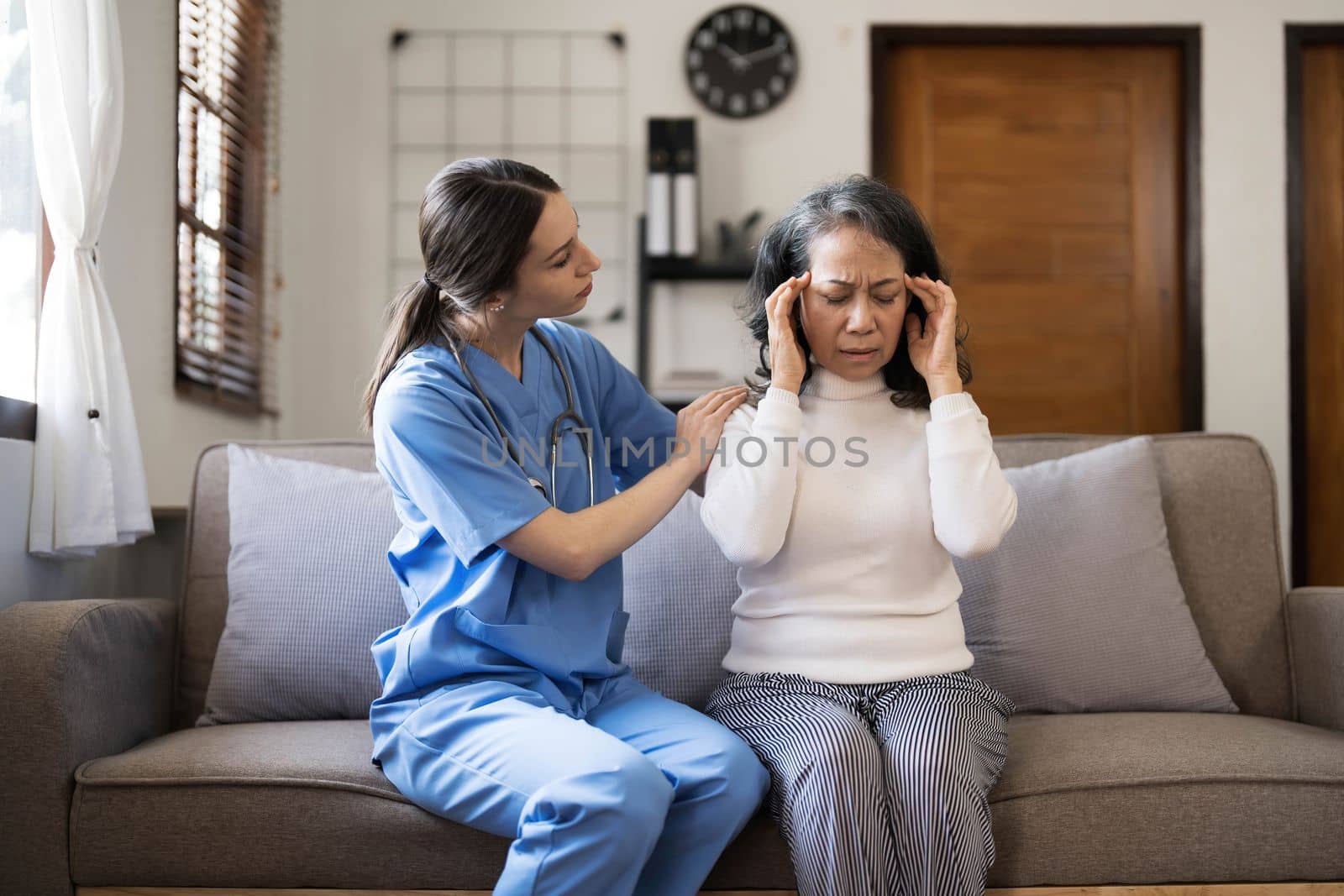 Young female physician leaning forward to elderly lady patient holding her hand in palms. supporting encouraging old person. by wichayada