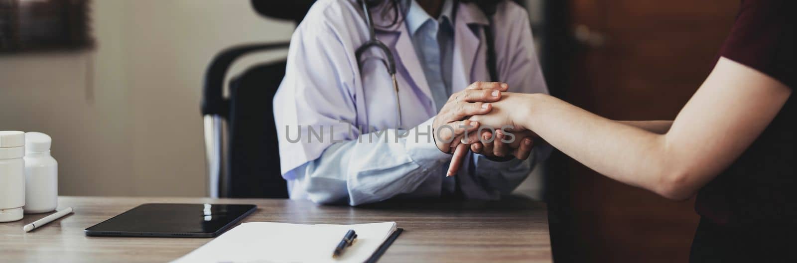 Happy patient is holding caregiver for a hand while spending time together. Elderly woman in nursing home and nurse..