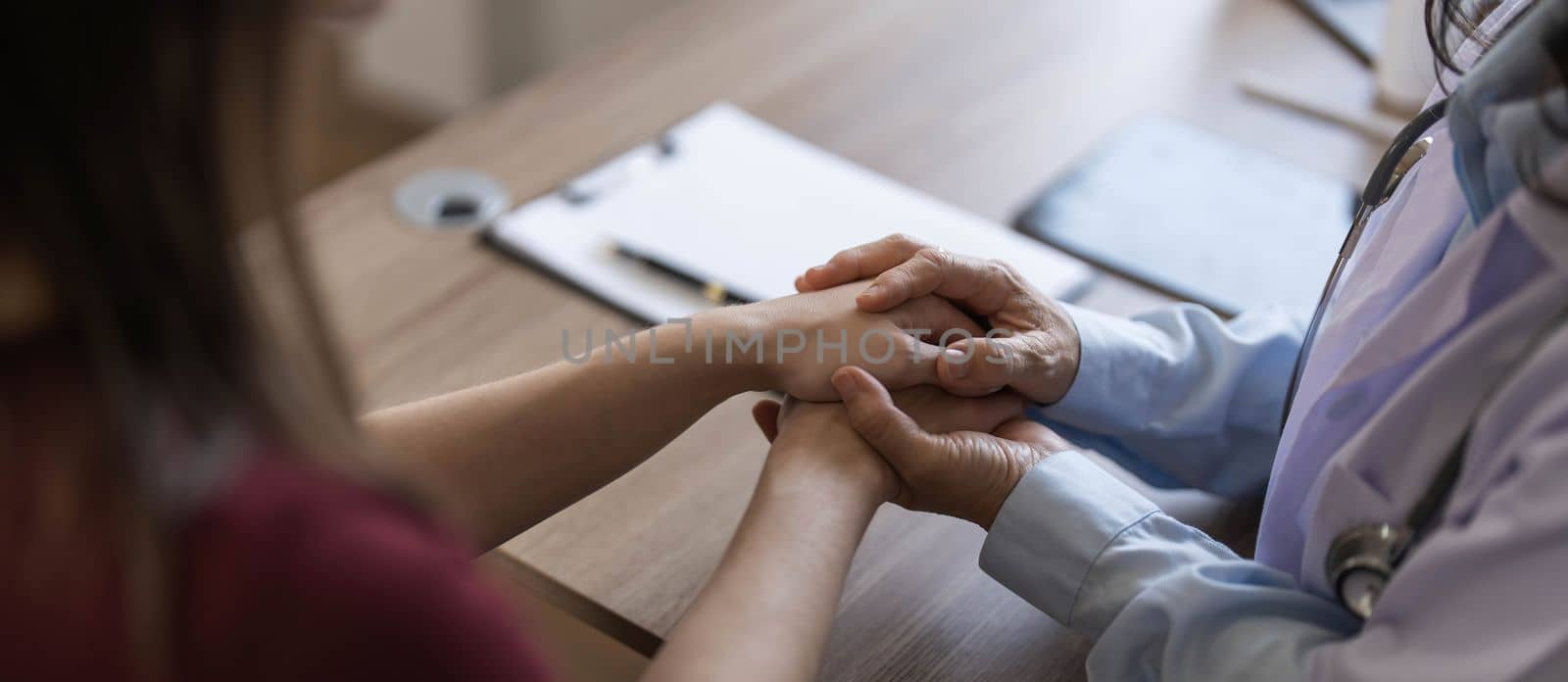 Happy patient is holding caregiver for a hand while spending time together. Elderly woman in nursing home and nurse..