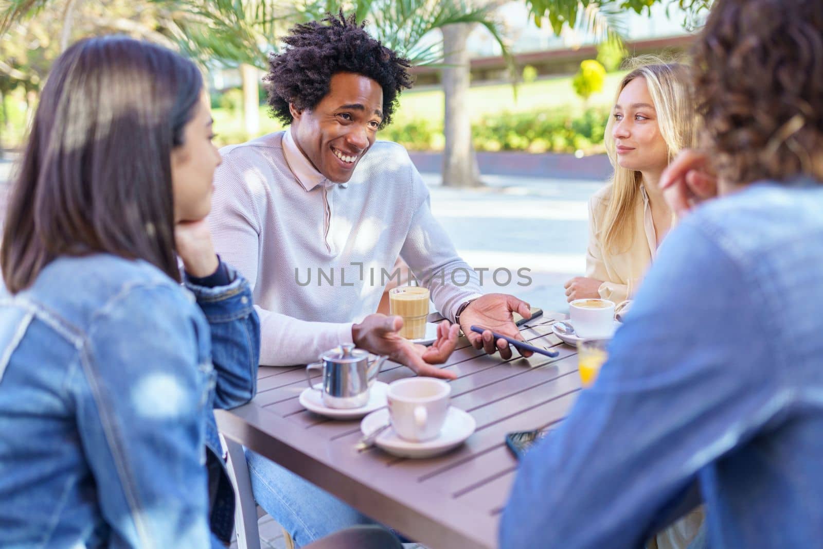 Multi-ethnic group of friends having a drink together in an outdoor bar. by javiindy