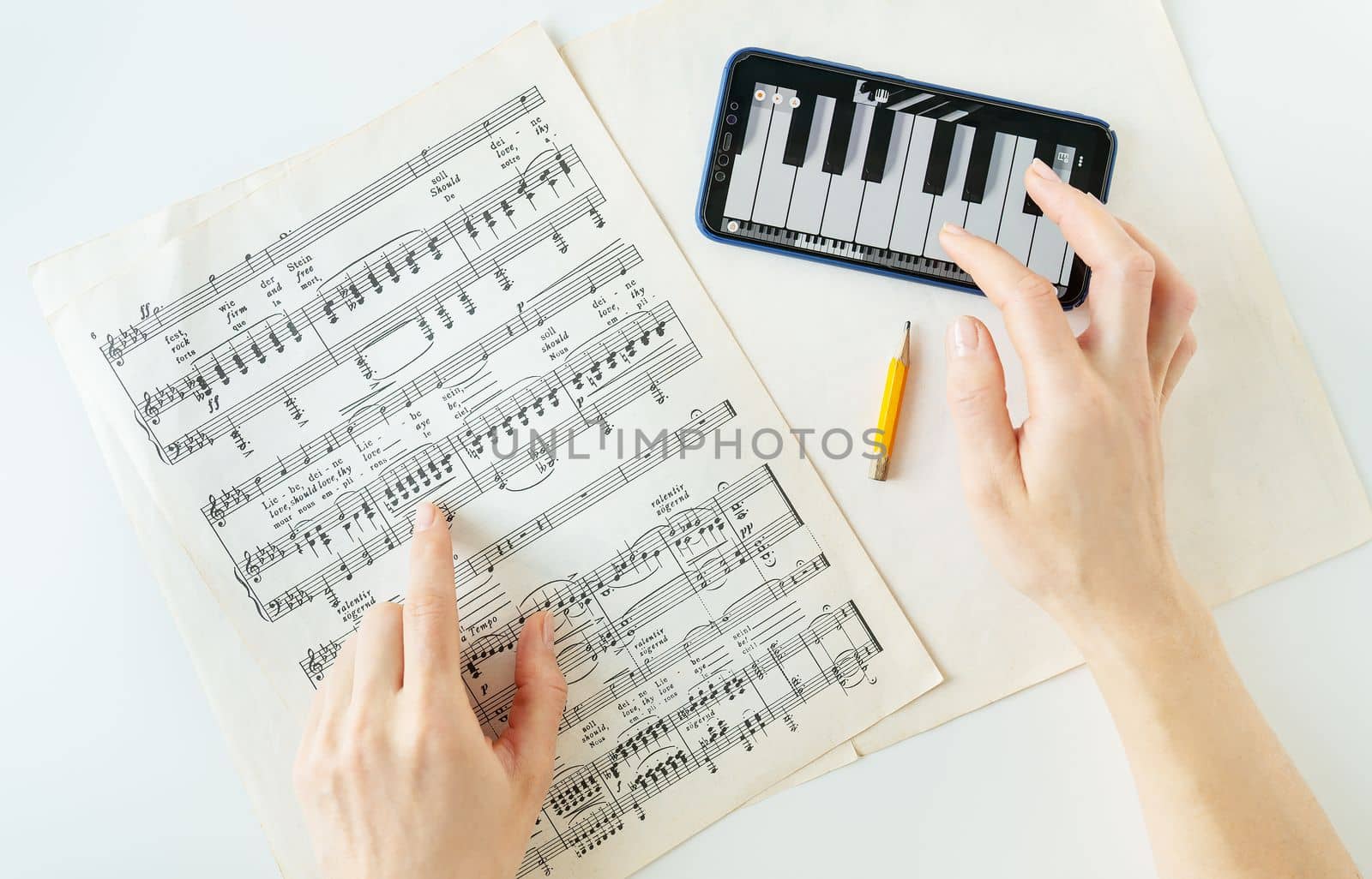 Lviv, Ukraine - December 13, 2022: The program on the phone to play the piano, piano score. Musical notes on paper. The program on the smartphone, practice. View from above