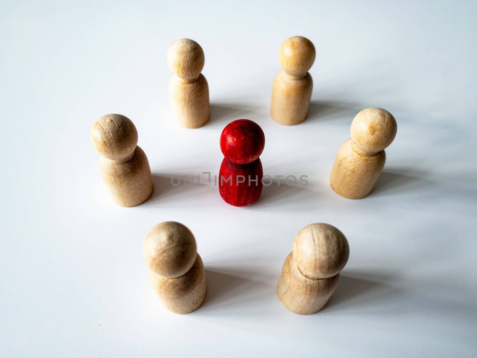Top side view of red wooden doll figure surrounded by other doll figure. Harassment concept.