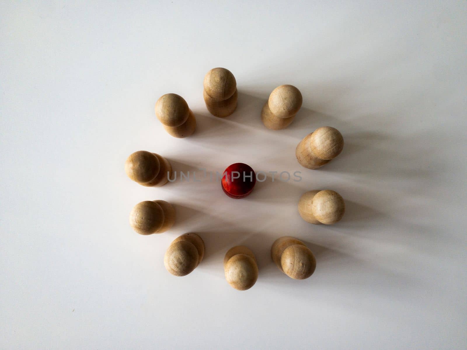 Top view of red wooden doll figure surrounded by other doll figure. Harassment concept.