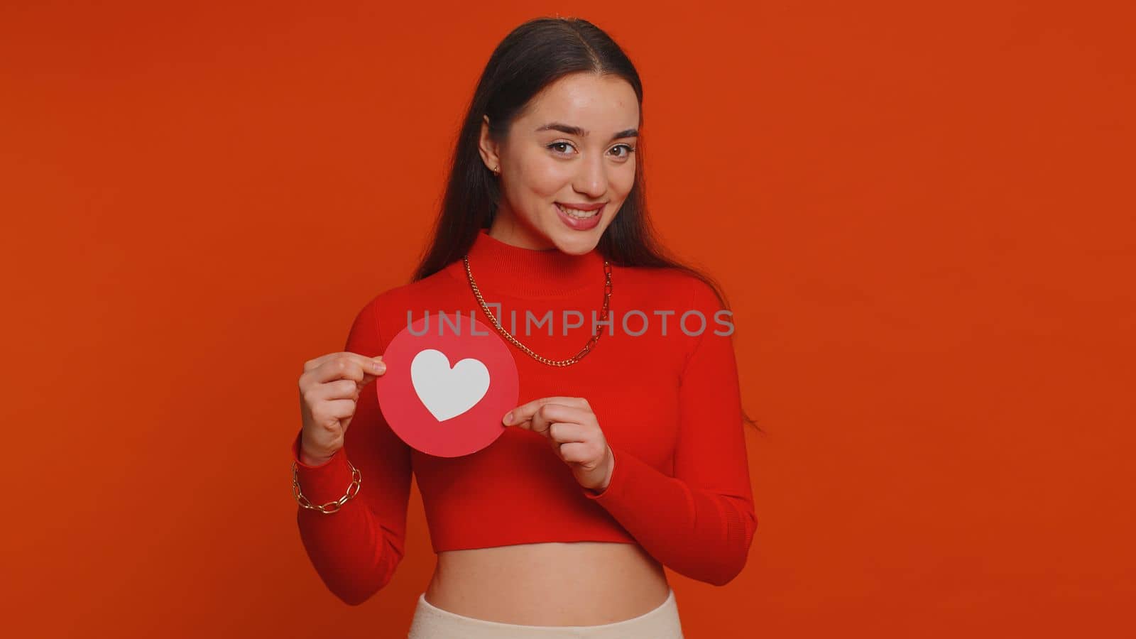 Like. Hipster one pretty woman show heart banner inscription agrees with something, gives positive reply recommends advertisement likes good. Young girl isolated alone on red studio wall background