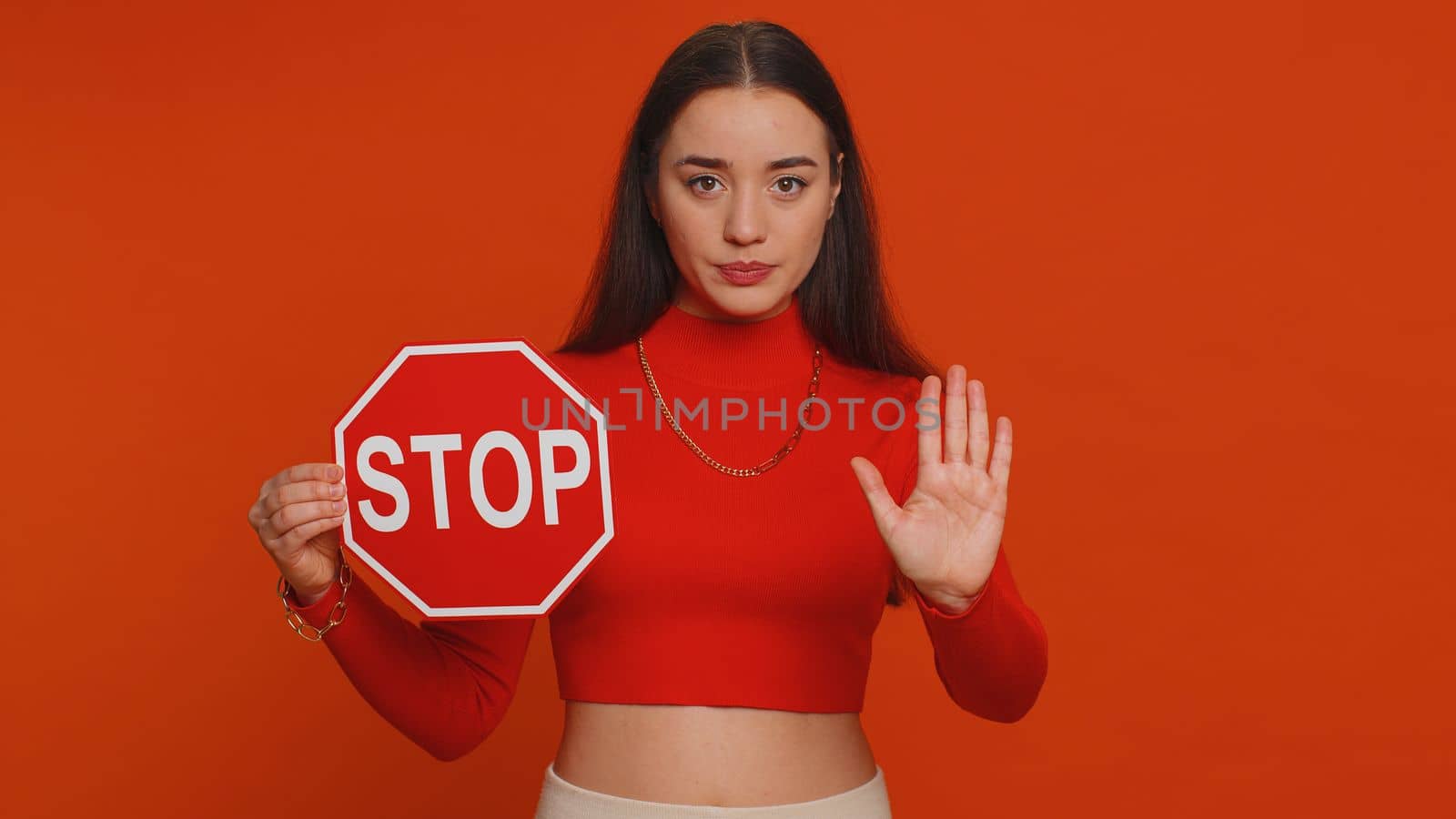 Serious pretty woman say No, hold inscription text red No stop danger sign, warning of finish, prohibited access declining communication, body language, trouble, protest. Girl on red background